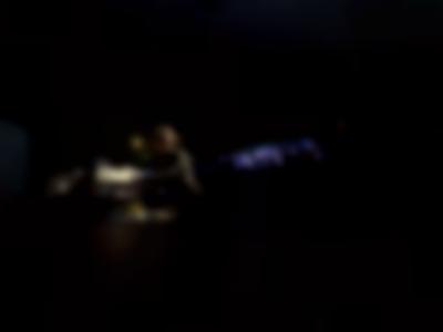 In a dark space, a person stands behind a control desk.