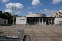 Across an empty square, a building is visible. On the left, channel letters spell out 
