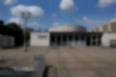 Across an empty square, a building is visible. On the left, channel letters spell out 
