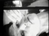 Black-and-white photograph showing Joan Jonas' face and half of her hand. The image has been rotated horizontally.