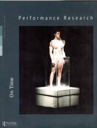 Blue page, with a photograph occupying the majority of the space. It shows a person on top of a square, white platform. They are standing inside a glass cuboid, up to their hips. Above the photograph, white text reads 