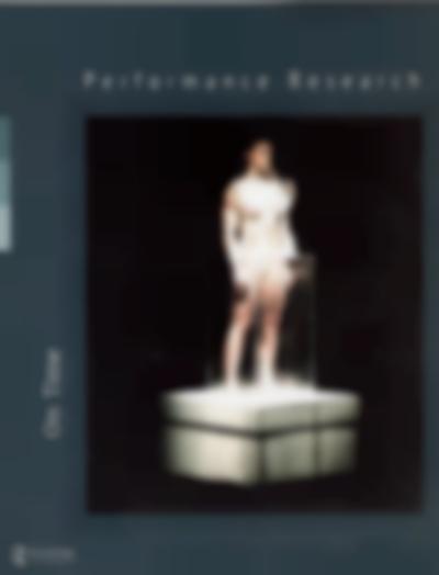Blue page, with a photograph occupying the majority of the space. It shows a person on top of a square, white platform. They are standing inside a glass cuboid, up to their hips. Above the photograph, white text reads 