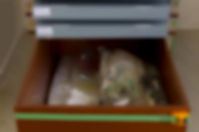 Wooden box with two plastic bags with paper and fabric inside. Above the box. There are two grey storage boxes with white stickers on the left side.