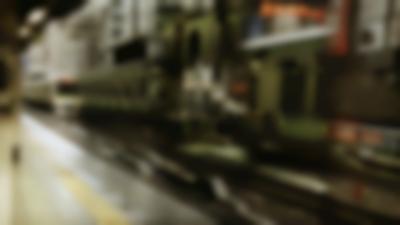 A moving train is arriving to the platform. There is some reflections in the image, perhaps from double exposure.