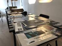 Table seen from above. Laid on the table are several photographs and other printed material.