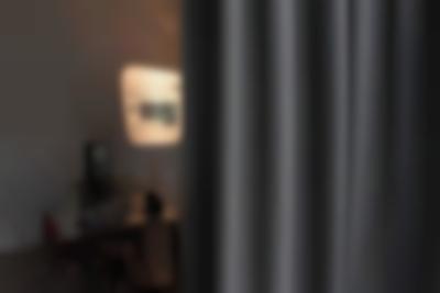 A grey curtain occupies two thirds of the image. To the left, a table with books and other printed materials is visible. An image and some text is being projected on the wall next to it.