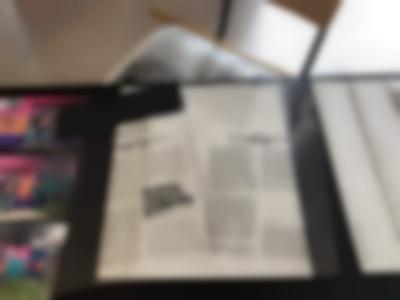 On a table with black cloth, two transparency sheets with black text have been left on top of a white booklet. The title of the right transparency sheet is 