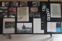 Table seen from above. Laid on the table are several photographs, printed texts, booklets and a few old photo slides.